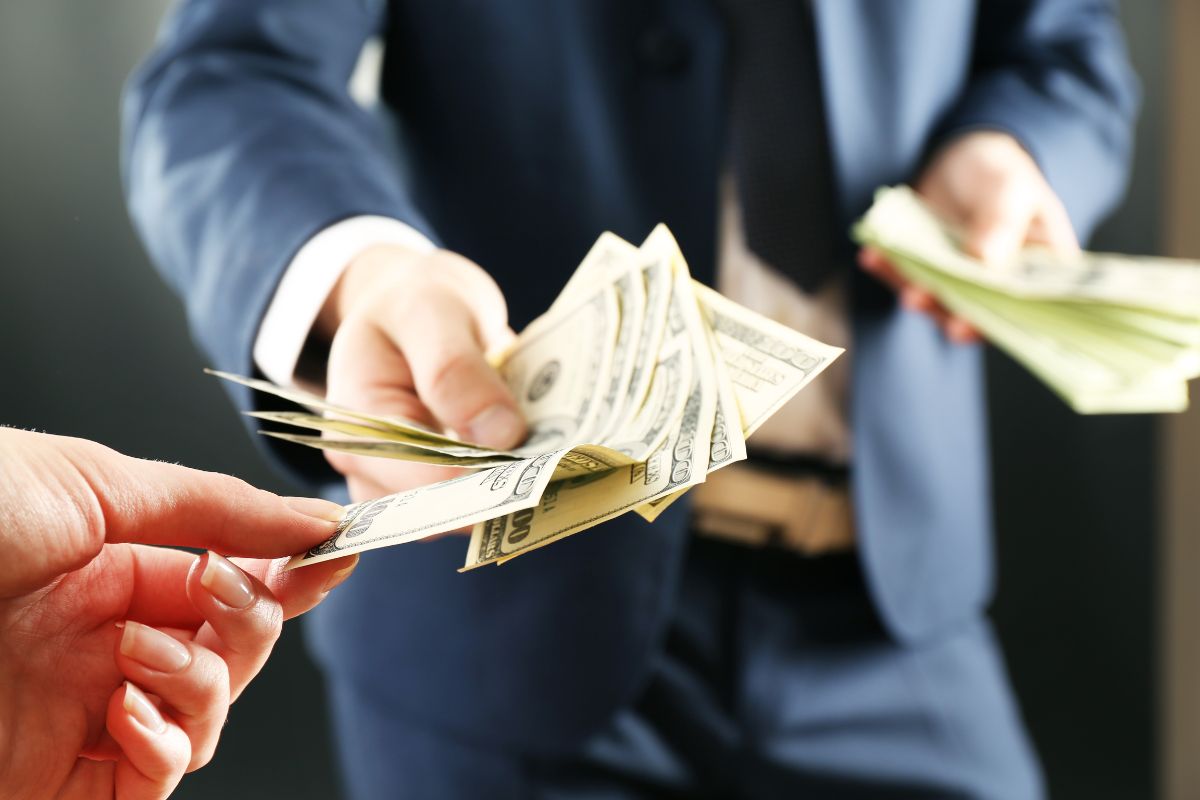 Person in a business suit handing over a stack of dollar bills, symbolizing a refund for a pet deposit on emotional support animals