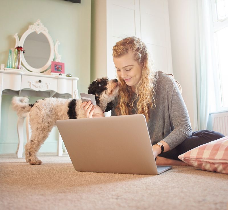 Woman working on laptop with dog next to her Woman working on laptop with dog next to her