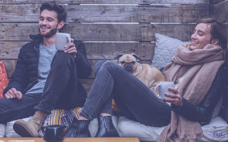 A couple relaxing outdoors with a small pug A couple relaxing outdoors with a small pug